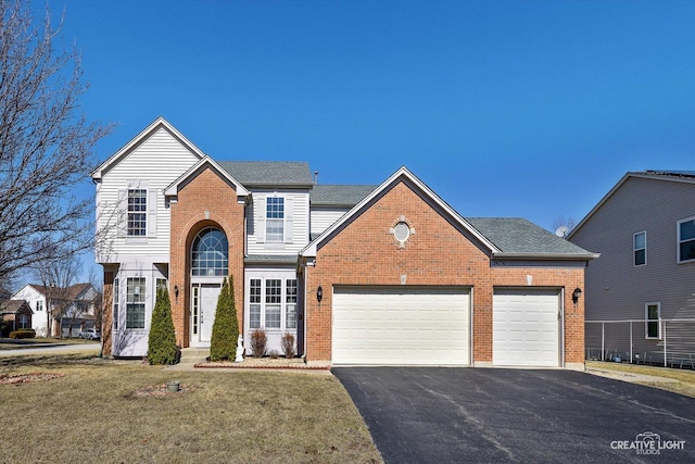 traditional home with brick siding, aphalt driveway, a front yard, roof with shingles, and a garage