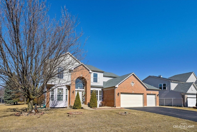 traditional-style home with brick siding, an attached garage, driveway, and a front lawn