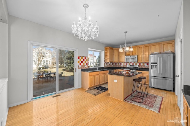 kitchen with open shelves, dark countertops, stainless steel appliances, light wood-style floors, and a chandelier