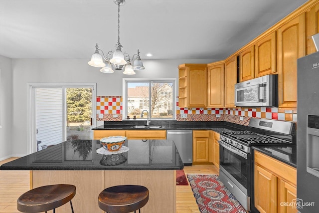 kitchen with a breakfast bar area, a sink, decorative backsplash, stainless steel appliances, and a center island