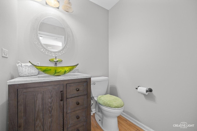 bathroom featuring toilet, vanity, baseboards, and wood finished floors