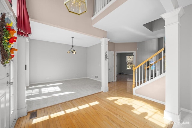 entryway featuring hardwood / wood-style floors, stairway, decorative columns, baseboards, and a towering ceiling