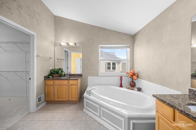 bathroom featuring tile patterned flooring, visible vents, lofted ceiling, and two vanities