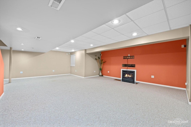 finished below grade area featuring a fireplace with flush hearth, baseboards, visible vents, and carpet floors