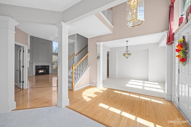 entryway featuring a wealth of natural light, hardwood / wood-style floors, a fireplace, stairs, and ornate columns