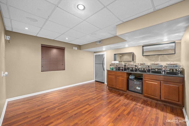 kitchen featuring dark countertops, visible vents, dark wood-type flooring, brown cabinetry, and stainless steel fridge