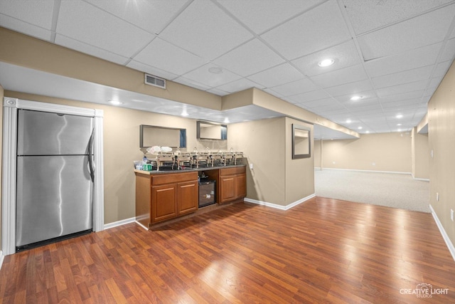 bar with a drop ceiling, dark wood-style floors, baseboards, and freestanding refrigerator