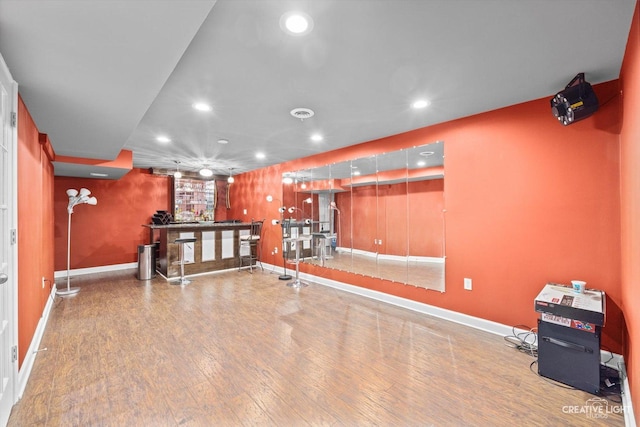 exercise room featuring recessed lighting, baseboards, wood finished floors, and a dry bar