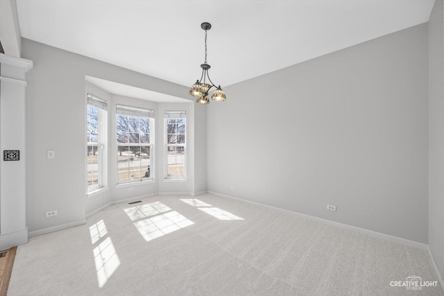 unfurnished dining area featuring an inviting chandelier, carpet flooring, and baseboards