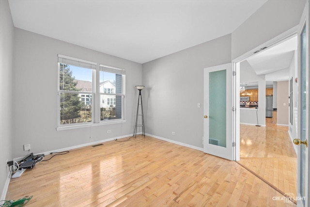 spare room with visible vents, light wood-style floors, and baseboards