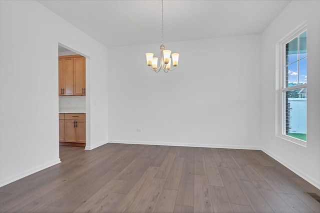 empty room featuring hardwood / wood-style flooring and an inviting chandelier