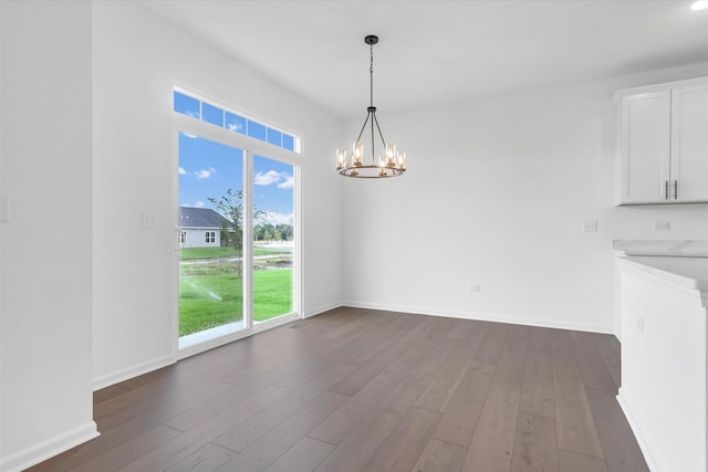 unfurnished dining area with a chandelier and dark hardwood / wood-style flooring