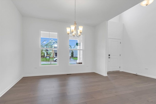 unfurnished room with a notable chandelier and dark wood-type flooring