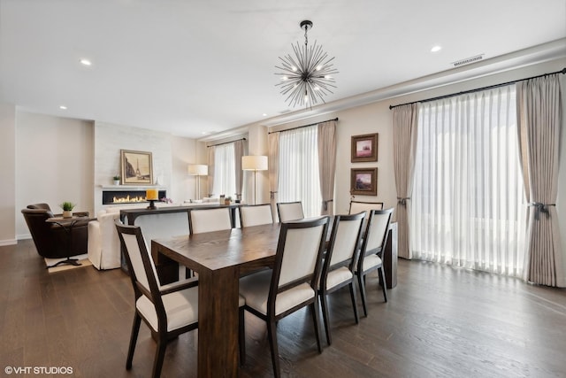 dining room featuring an inviting chandelier, a fireplace, and dark wood-type flooring