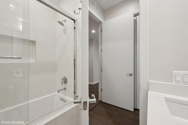 bathroom featuring hardwood / wood-style flooring and bath / shower combo with glass door