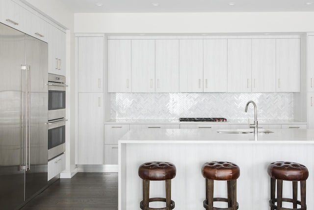 kitchen with white cabinetry, sink, a kitchen breakfast bar, and appliances with stainless steel finishes