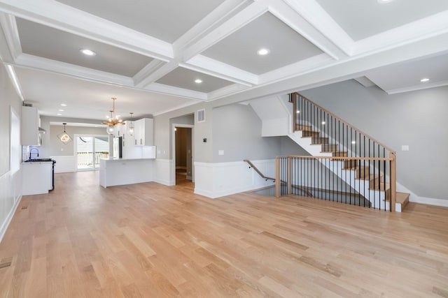 unfurnished living room featuring beamed ceiling, coffered ceiling, an inviting chandelier, and light hardwood / wood-style flooring