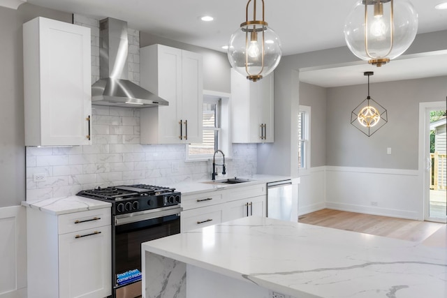 kitchen with wall chimney range hood, sink, dishwasher, gas range oven, and white cabinets