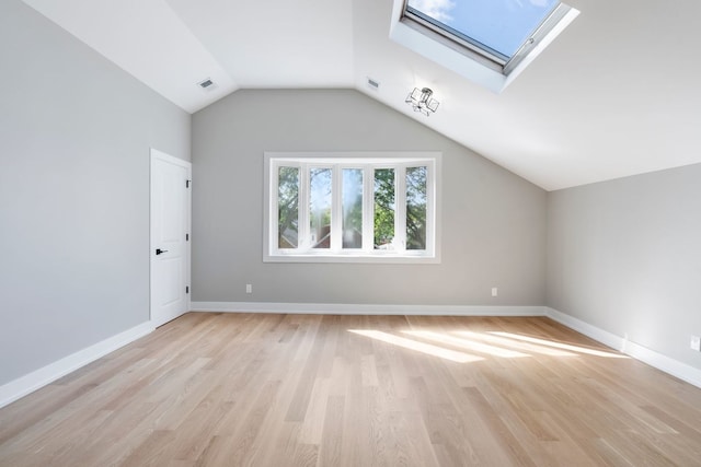 additional living space with lofted ceiling with skylight and light hardwood / wood-style floors