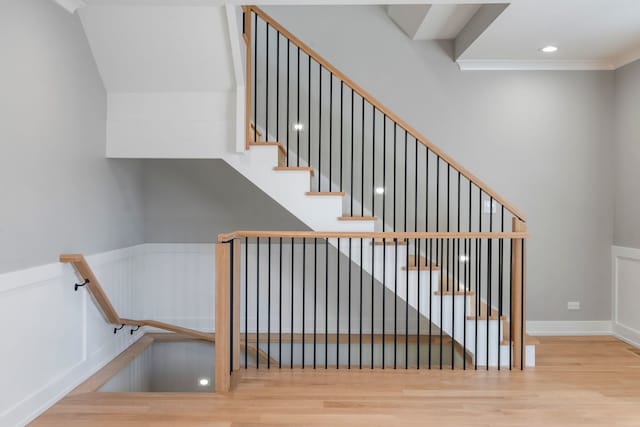 staircase with ornamental molding and hardwood / wood-style floors