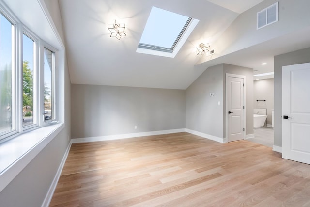 bonus room featuring vaulted ceiling with skylight and light wood-type flooring