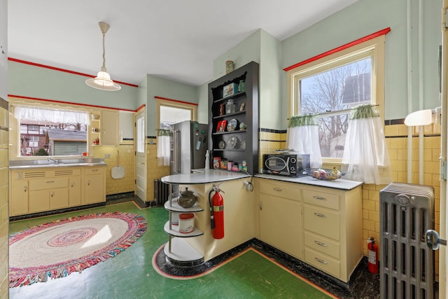 kitchen featuring radiator, tile walls, cream cabinets, and open shelves