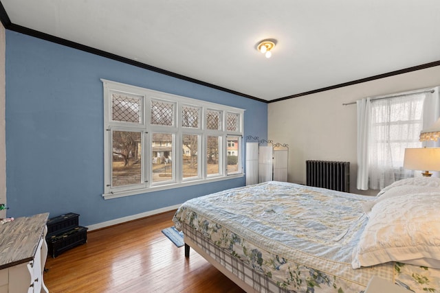 bedroom featuring baseboards, crown molding, radiator heating unit, and wood finished floors