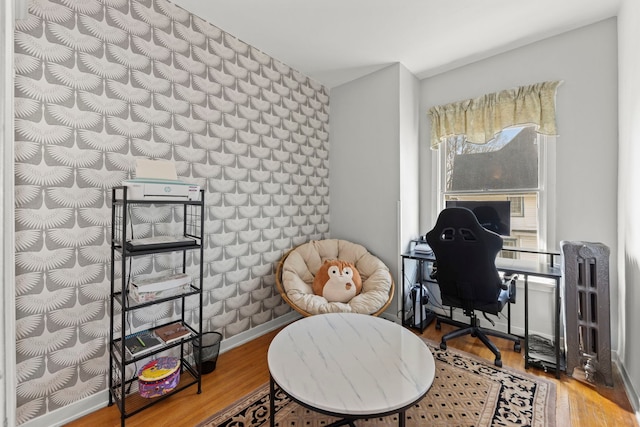 office featuring an accent wall, wood finished floors, and baseboards