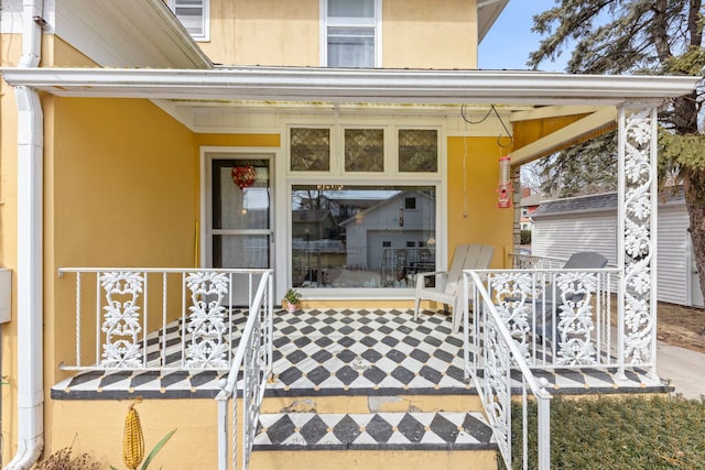 doorway to property with a porch and stucco siding