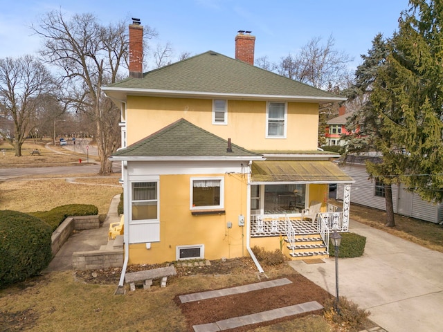 back of property with driveway, a chimney, roof with shingles, a porch, and stucco siding