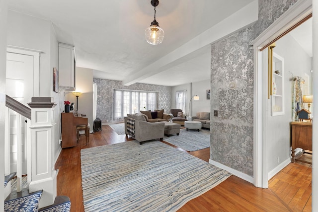 living area with wallpapered walls, wood finished floors, beamed ceiling, baseboards, and stairs