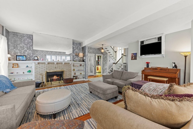 living area with stairs, a brick fireplace, and wood finished floors