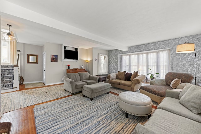 living room featuring baseboards, stairway, wood finished floors, and wallpapered walls