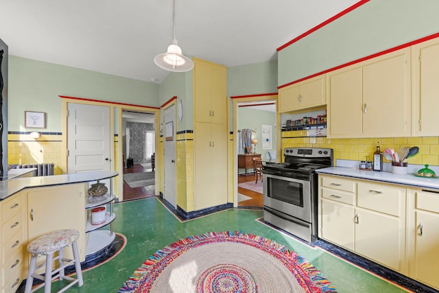 kitchen featuring tasteful backsplash, dark floors, electric stove, and cream cabinetry