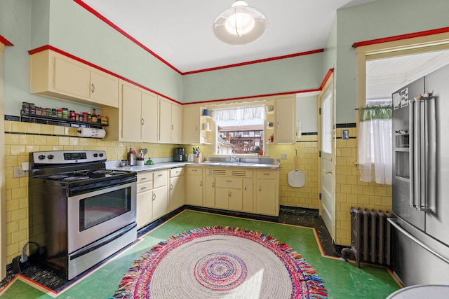 kitchen with a sink, tile walls, light countertops, appliances with stainless steel finishes, and radiator heating unit