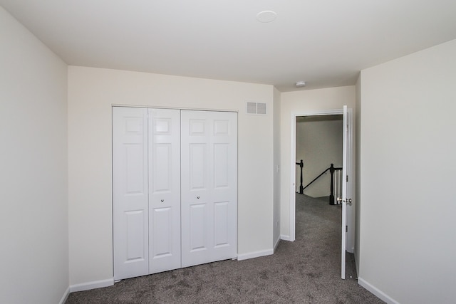 unfurnished bedroom with a closet and dark colored carpet