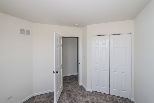 unfurnished bedroom featuring dark carpet and a closet