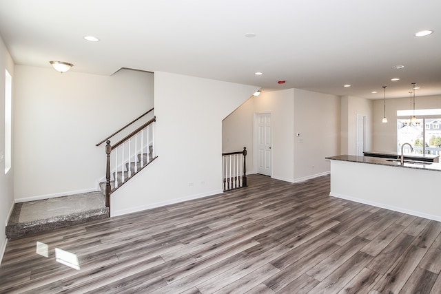 unfurnished living room with sink, dark hardwood / wood-style floors, and a chandelier