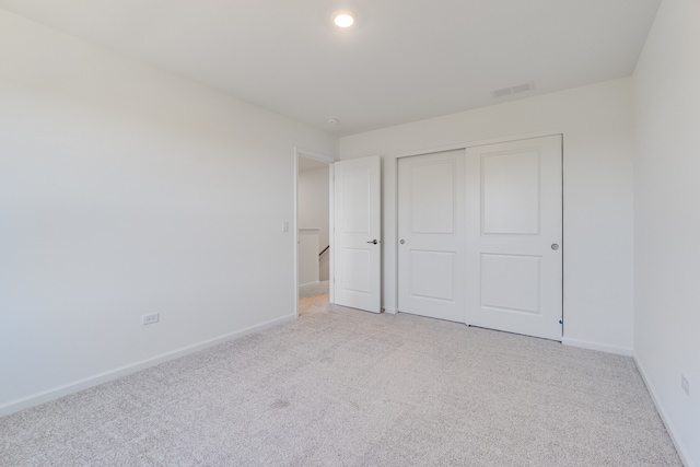 unfurnished bedroom with light colored carpet and a closet