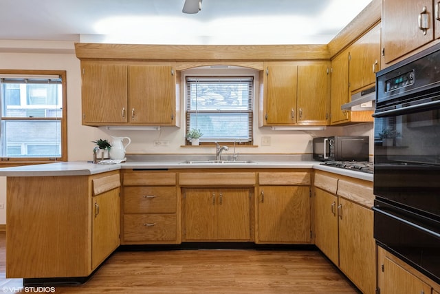 kitchen with kitchen peninsula, sink, light hardwood / wood-style flooring, and black appliances