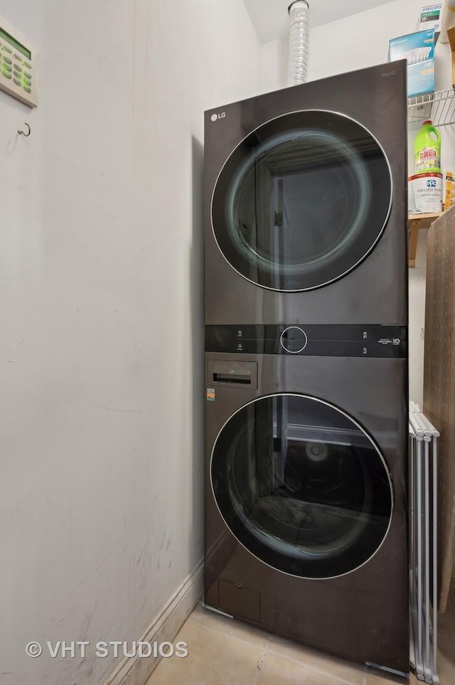 laundry area featuring stacked washer and dryer and light tile patterned floors