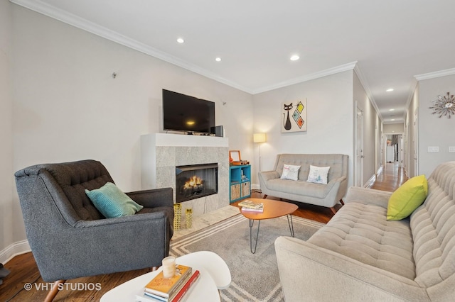 living room featuring ornamental molding, a tiled fireplace, and hardwood / wood-style floors