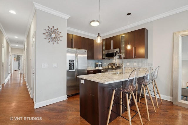 kitchen featuring pendant lighting, dark brown cabinets, stainless steel appliances, a kitchen bar, and kitchen peninsula