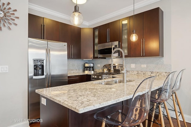 kitchen with hanging light fixtures, stainless steel appliances, kitchen peninsula, and a kitchen bar