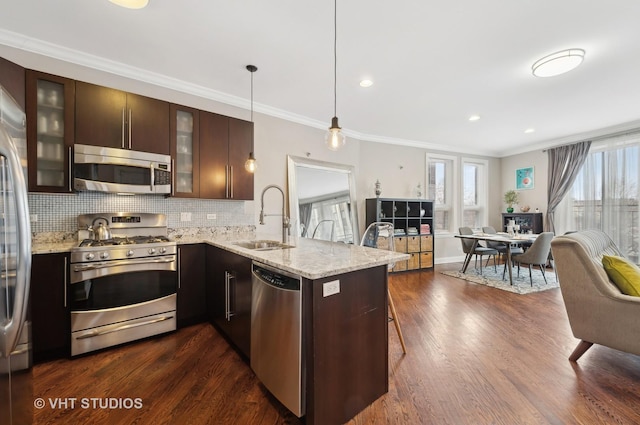 kitchen with appliances with stainless steel finishes, sink, dark brown cabinetry, and kitchen peninsula