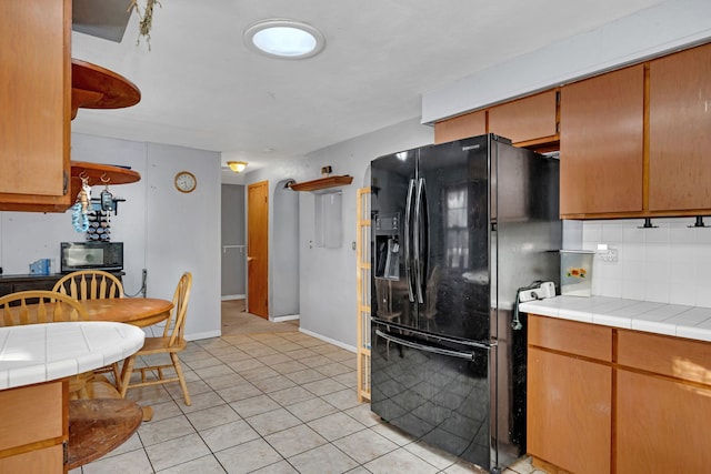 kitchen featuring light tile patterned floors, decorative backsplash, tile countertops, and black appliances