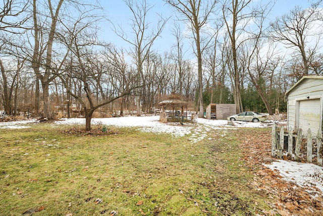 yard layered in snow with a gazebo and a garage