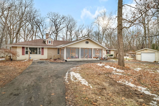 ranch-style home with an outbuilding, a garage, and a sunroom