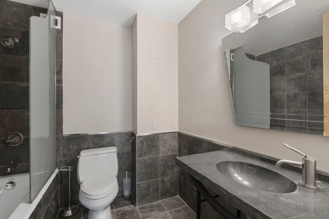 full bathroom featuring tiled shower / bath, sink, tile walls, tile patterned flooring, and toilet