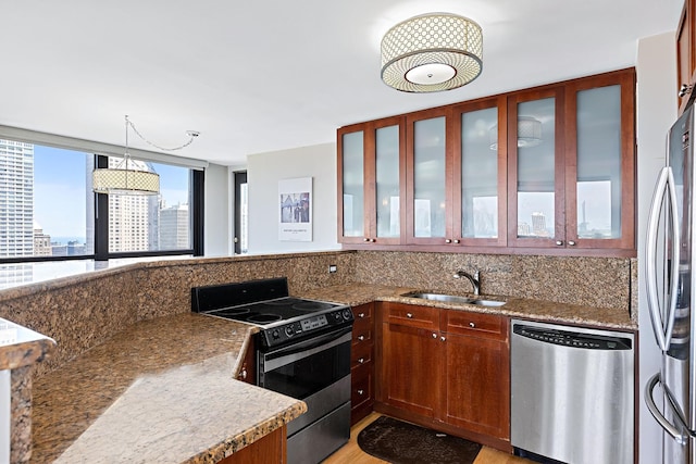 kitchen with appliances with stainless steel finishes, decorative light fixtures, sink, decorative backsplash, and light stone countertops